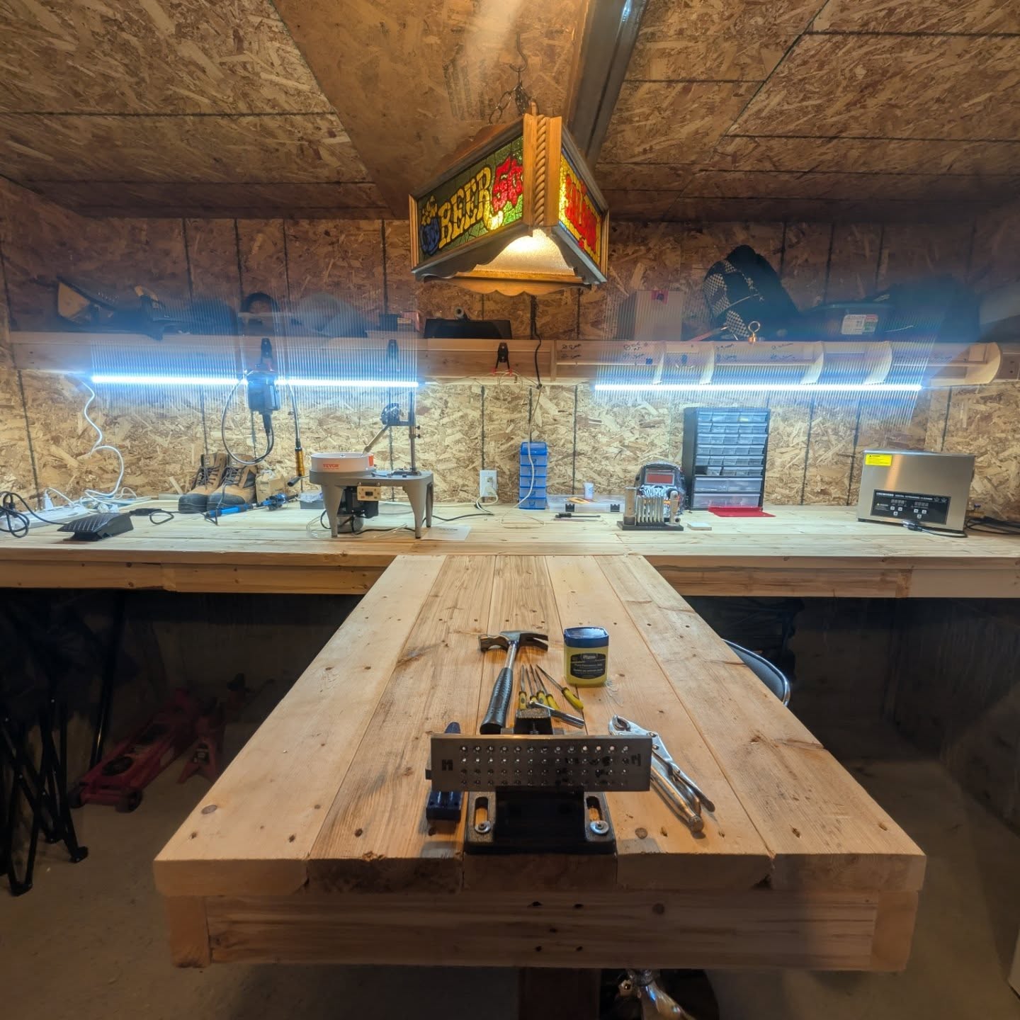 Workshop with wooden workbench, tools, and lighting fixtures.